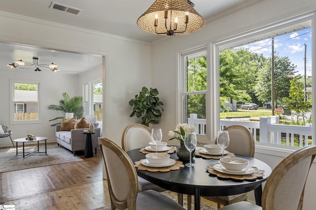 dining room with a wealth of natural light, visible vents, hardwood / wood-style floors, and a chandelier