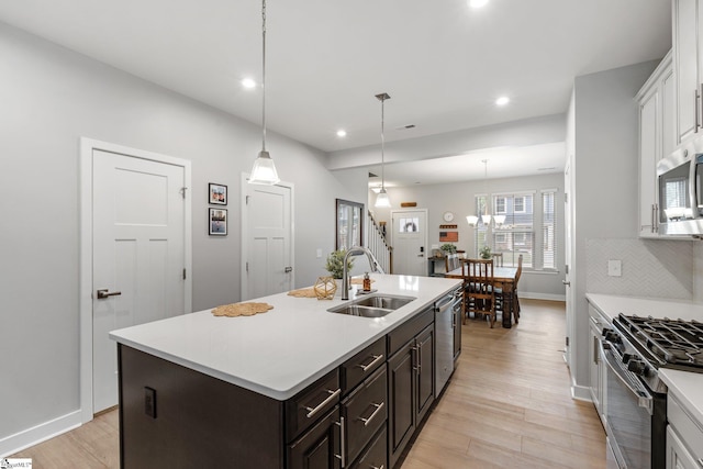 kitchen featuring light wood-type flooring, a sink, light countertops, stainless steel appliances, and recessed lighting
