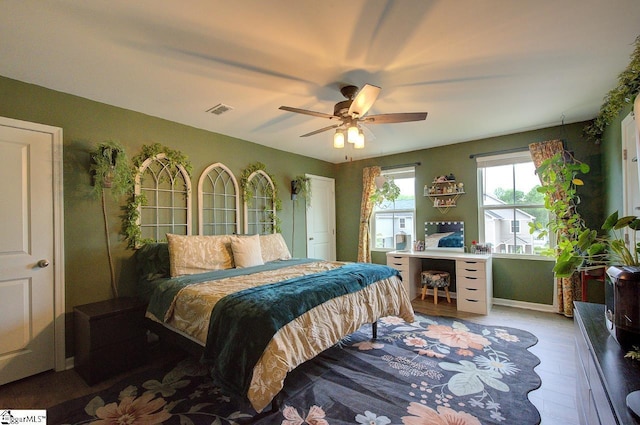 bedroom with a ceiling fan, visible vents, and wood finished floors