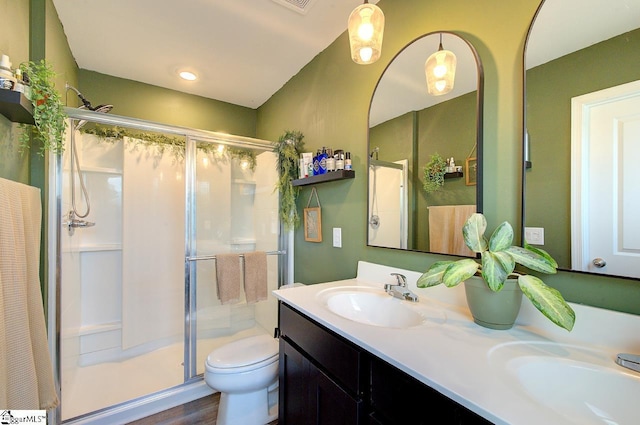 full bathroom featuring double vanity, toilet, a sink, and a stall shower