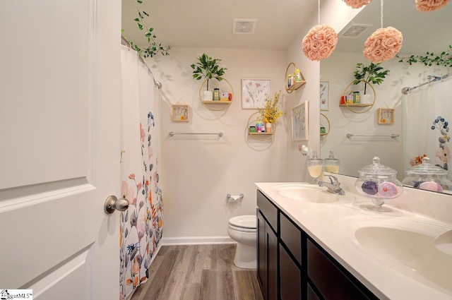 full bathroom with toilet, visible vents, a sink, and wood finished floors