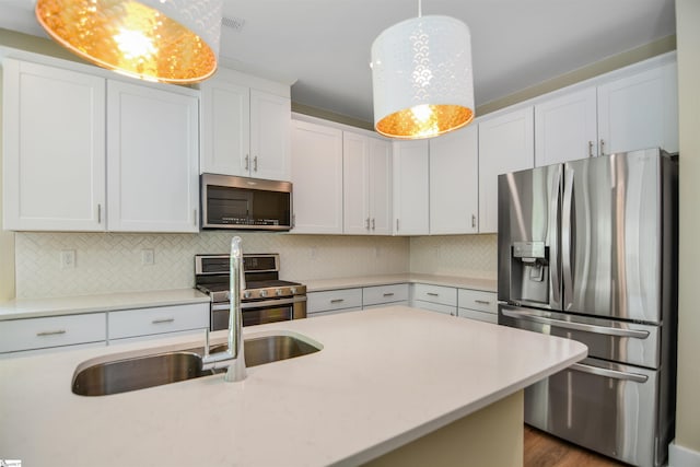 kitchen featuring decorative backsplash, pendant lighting, light countertops, a sink, and stainless steel appliances
