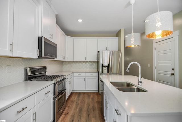 kitchen with a kitchen island with sink, dark wood-type flooring, light countertops, a sink, and stainless steel appliances