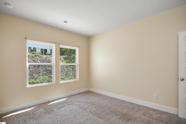 carpeted empty room featuring baseboards and visible vents