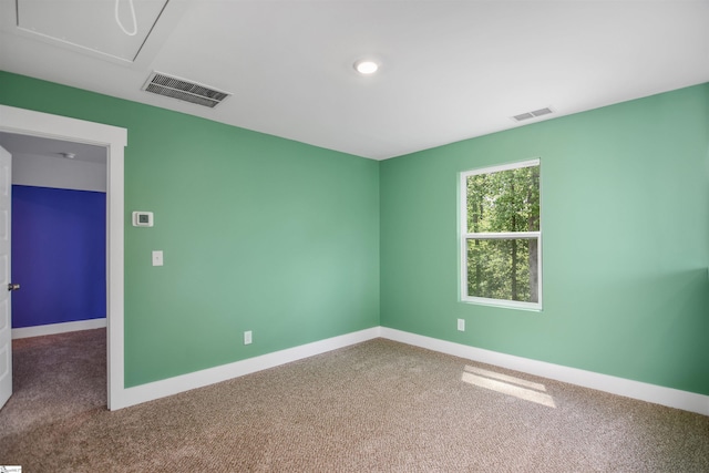 carpeted empty room featuring baseboards and visible vents