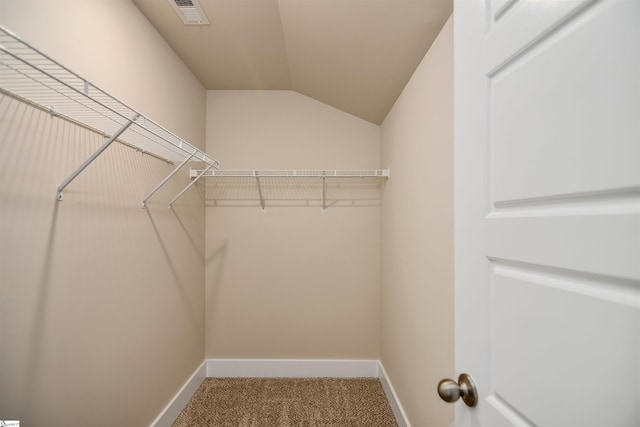 spacious closet featuring visible vents, carpet flooring, and vaulted ceiling