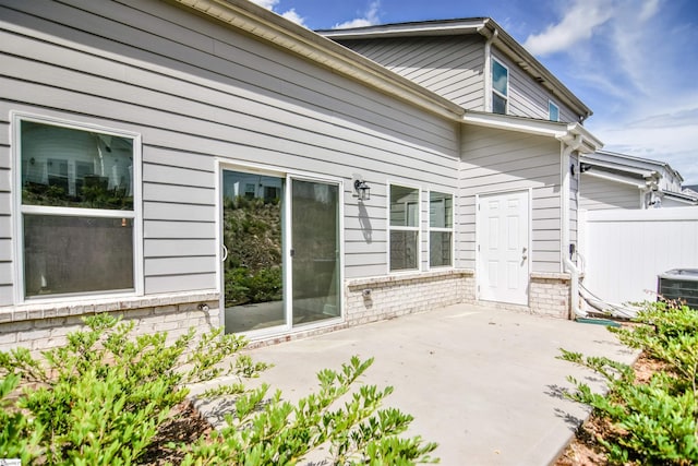 rear view of house featuring fence, a patio area, central AC, and brick siding