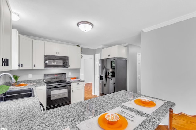 kitchen with white cabinetry, ornamental molding, a sink, and black appliances