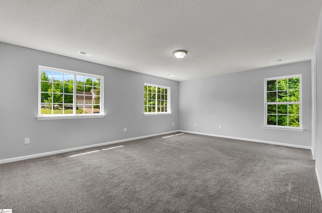 spare room featuring baseboards, dark carpet, and visible vents
