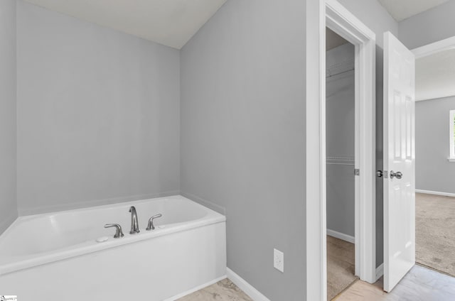 bathroom featuring baseboards, marble finish floor, and a garden tub