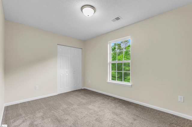 unfurnished bedroom featuring carpet floors, baseboards, a closet, and visible vents