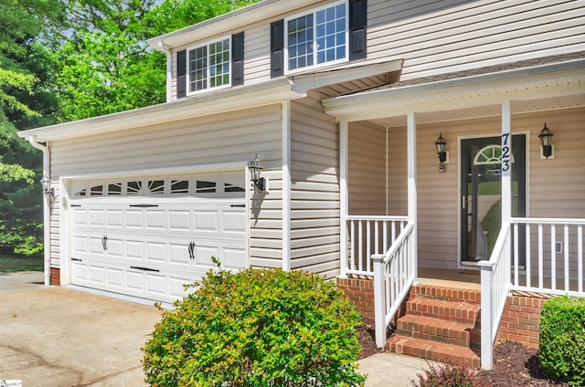 entrance to property featuring a porch, an attached garage, and driveway
