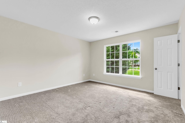 empty room with baseboards, carpet flooring, and visible vents