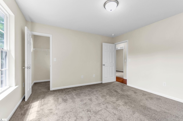 unfurnished bedroom featuring carpet flooring, baseboards, a spacious closet, and a closet