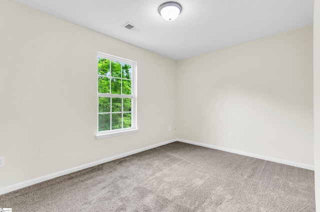 empty room featuring visible vents, carpet, and baseboards
