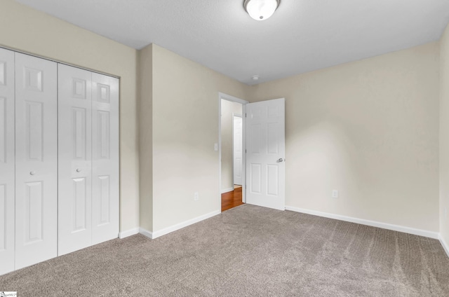 unfurnished bedroom with a closet, baseboards, and carpet flooring
