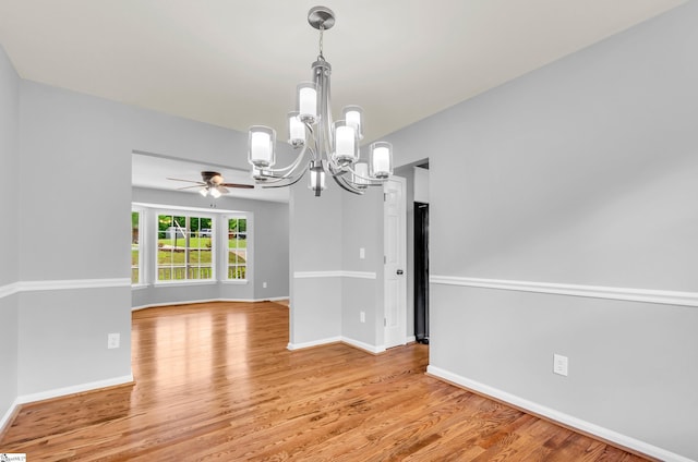 unfurnished dining area featuring baseboards, light wood-style flooring, and ceiling fan with notable chandelier