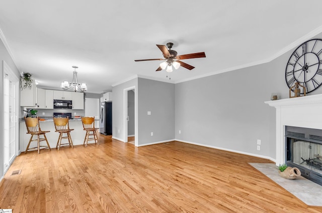 unfurnished living room featuring ornamental molding, light wood-style flooring, ceiling fan with notable chandelier, and a multi sided fireplace