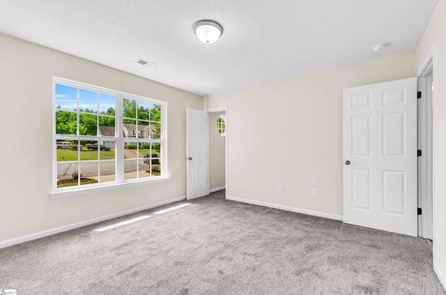 carpeted empty room featuring baseboards and visible vents