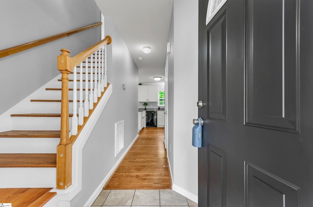 entrance foyer with baseboards, visible vents, light tile patterned floors, and stairway