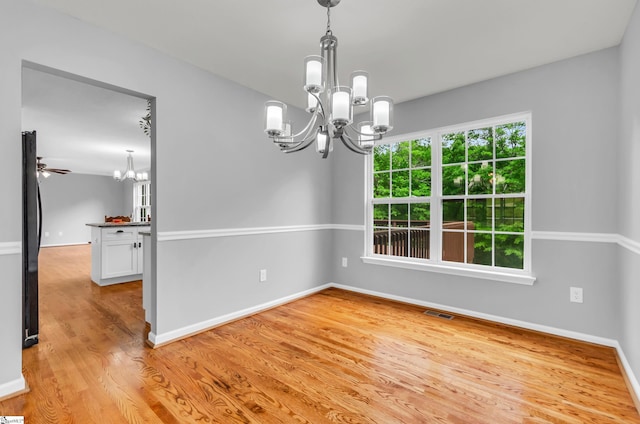 unfurnished dining area with visible vents, light wood-style flooring, baseboards, and a chandelier