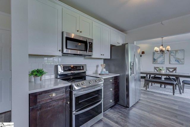 106 Hickory Valley Way, Taylors, SC 29687 - kitchen with crown molding, an inviting chandelier, dark wood-type flooring, tasteful backsplash, and appliances with stainless steel finishes