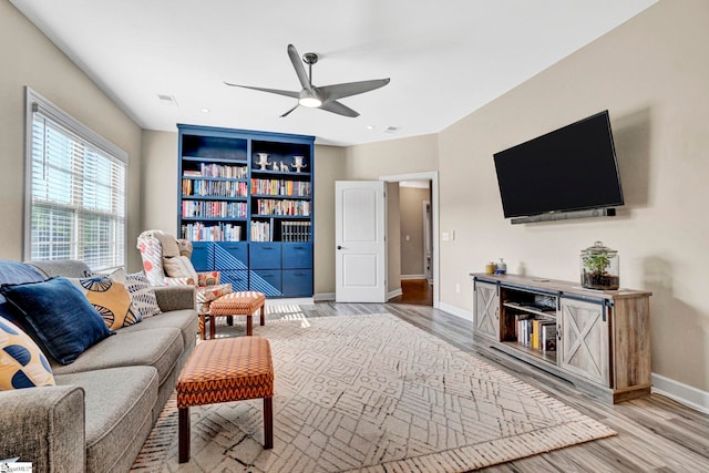 living area with baseboards, ceiling fan, and wood finished floors