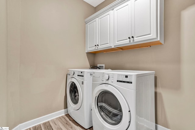 washroom featuring baseboards, light wood finished floors, cabinet space, and washing machine and clothes dryer