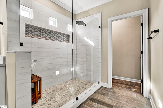 full bath with wood finish floors, baseboards, a tile shower, and ornamental molding