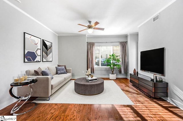 living area with ceiling fan, visible vents, crown molding, wood finished floors, and baseboards
