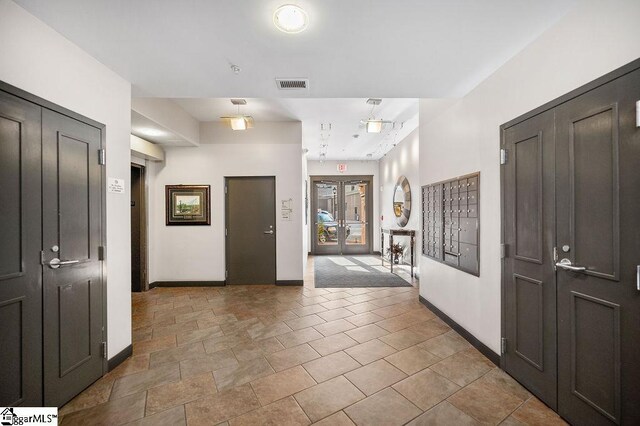 entryway featuring baseboards, visible vents, and mail area