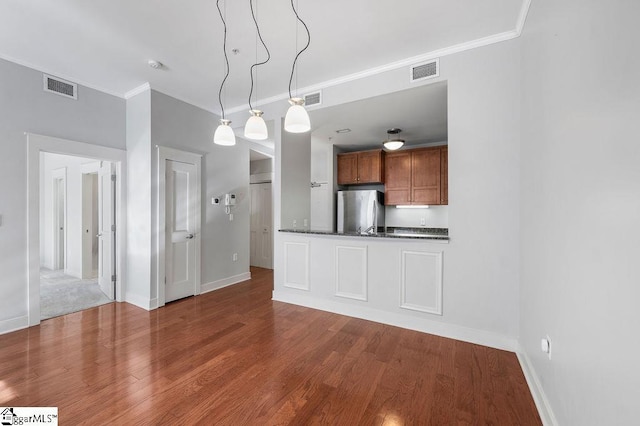 kitchen with visible vents, freestanding refrigerator, dark countertops, and ornamental molding