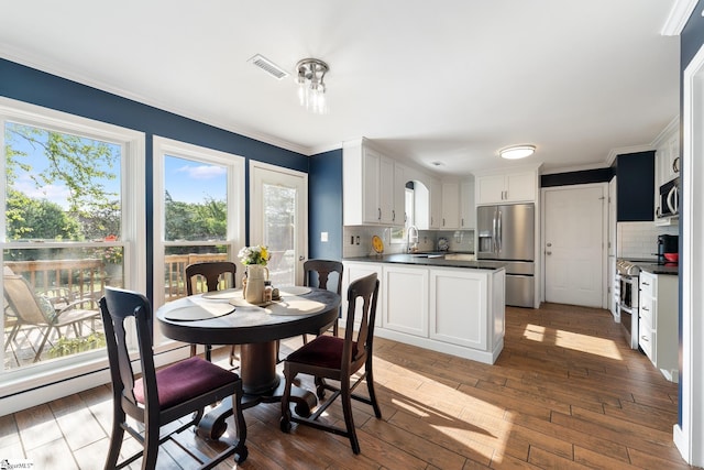 dining area with a wealth of natural light, ornamental molding, hardwood / wood-style floors, and visible vents