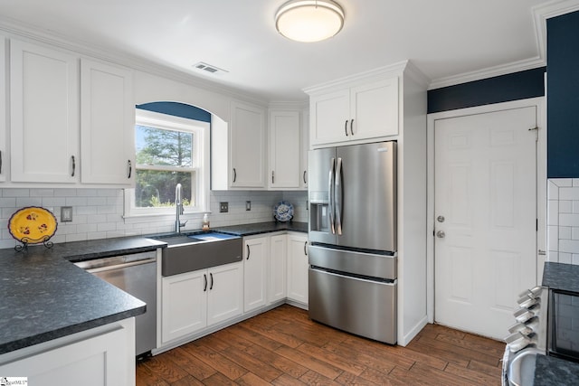 kitchen featuring visible vents, dark countertops, appliances with stainless steel finishes, a sink, and dark wood-style floors