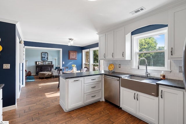 kitchen with stainless steel dishwasher, a sink, visible vents, and dark countertops