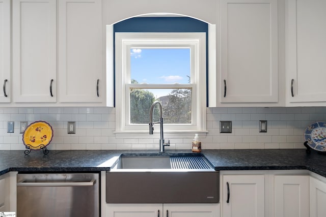 kitchen with a sink, dark countertops, stainless steel dishwasher, and white cabinetry