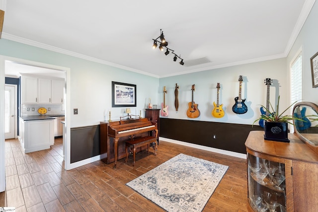 interior space with crown molding, track lighting, baseboards, and wood finished floors