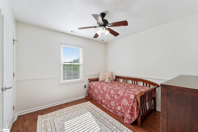 bedroom with a ceiling fan, a textured ceiling, visible vents, wood finished floors, and baseboards