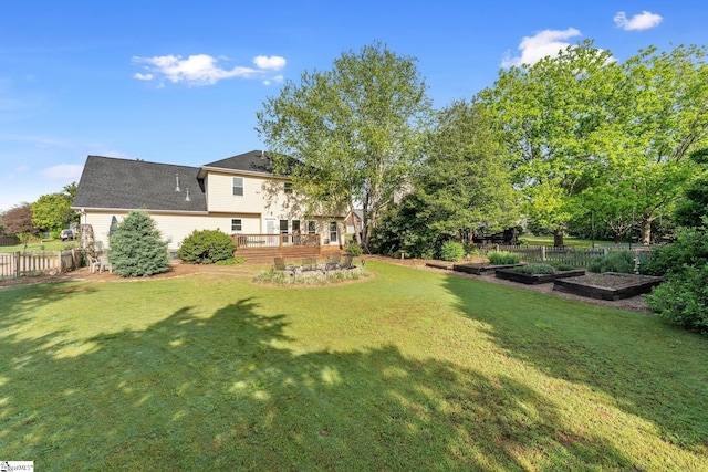 view of yard with fence, a wooden deck, and a garden