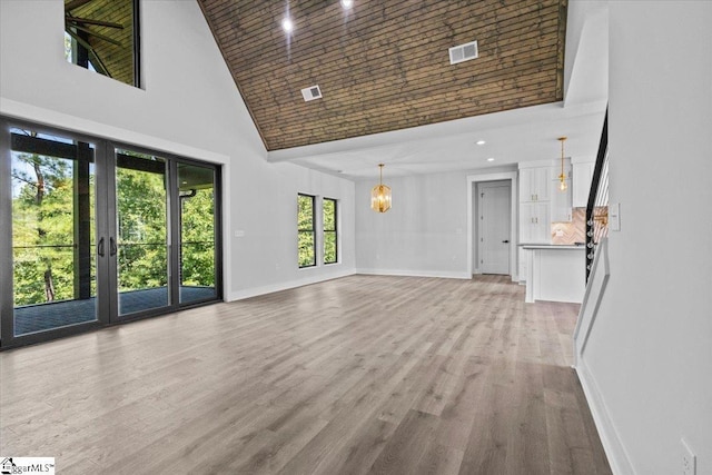 unfurnished living room featuring visible vents, light wood-type flooring, high vaulted ceiling, baseboards, and a notable chandelier