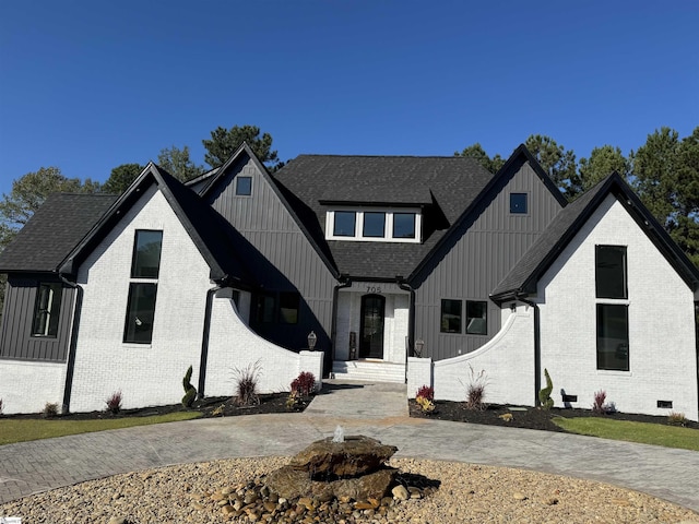 modern farmhouse style home featuring board and batten siding, brick siding, and a shingled roof