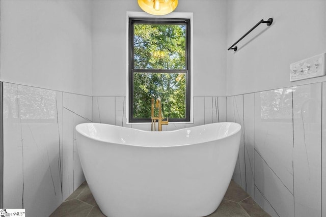 full bath with a wainscoted wall and a soaking tub