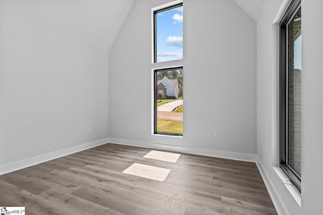 bonus room with baseboards, wood finished floors, and high vaulted ceiling