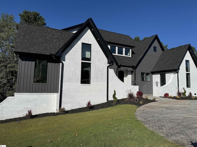 view of front of house featuring brick siding, a front lawn, and board and batten siding