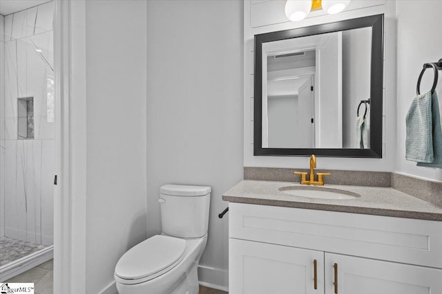 bathroom with vanity, baseboards, a shower stall, and toilet