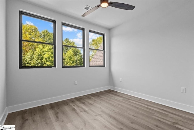 unfurnished room featuring ceiling fan, visible vents, plenty of natural light, and wood finished floors