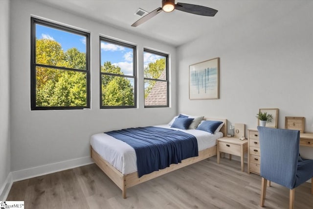 bedroom featuring baseboards, ceiling fan, wood finished floors, and visible vents