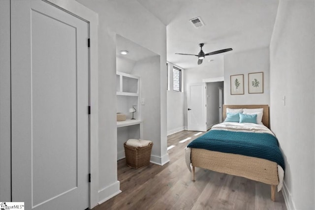 bedroom with a ceiling fan, baseboards, visible vents, and wood finished floors