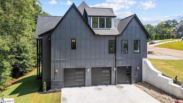 view of front of home with a garage, board and batten siding, roof with shingles, and a front yard