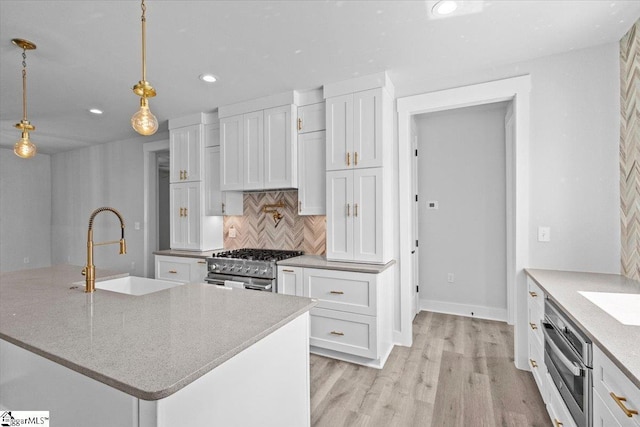 kitchen with tasteful backsplash, a sink, white cabinets, stainless steel appliances, and recessed lighting